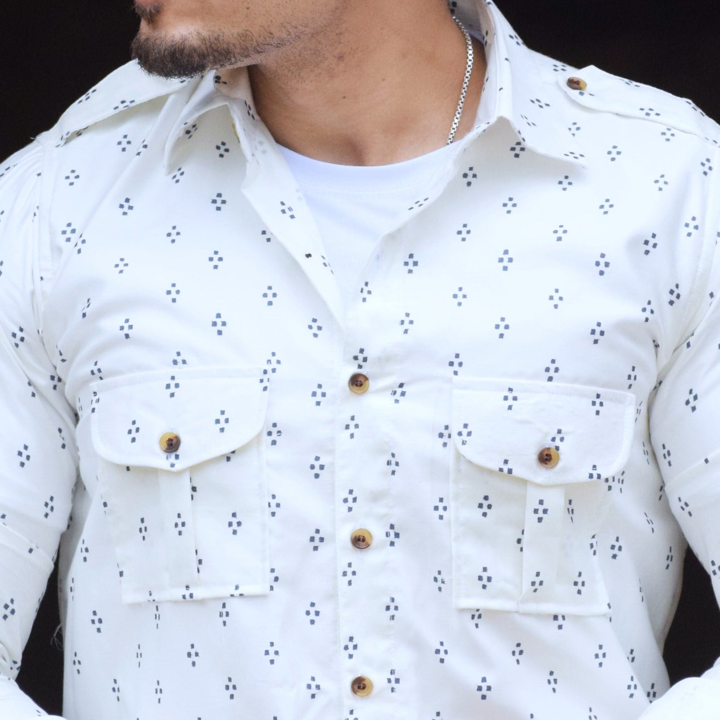 Man wearing a white patterned shirt against a black background