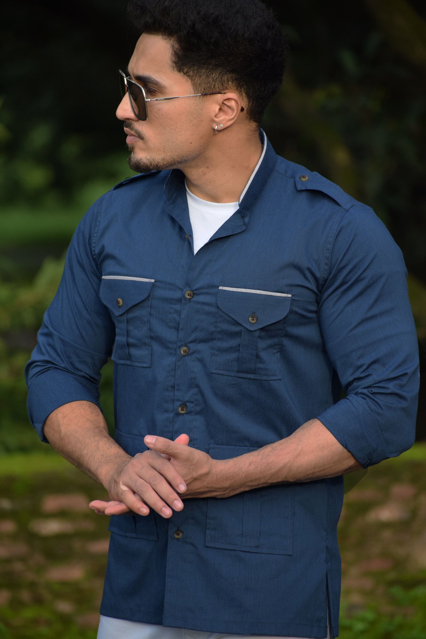 Man wearing a blue shirt with sunglasses outdoors