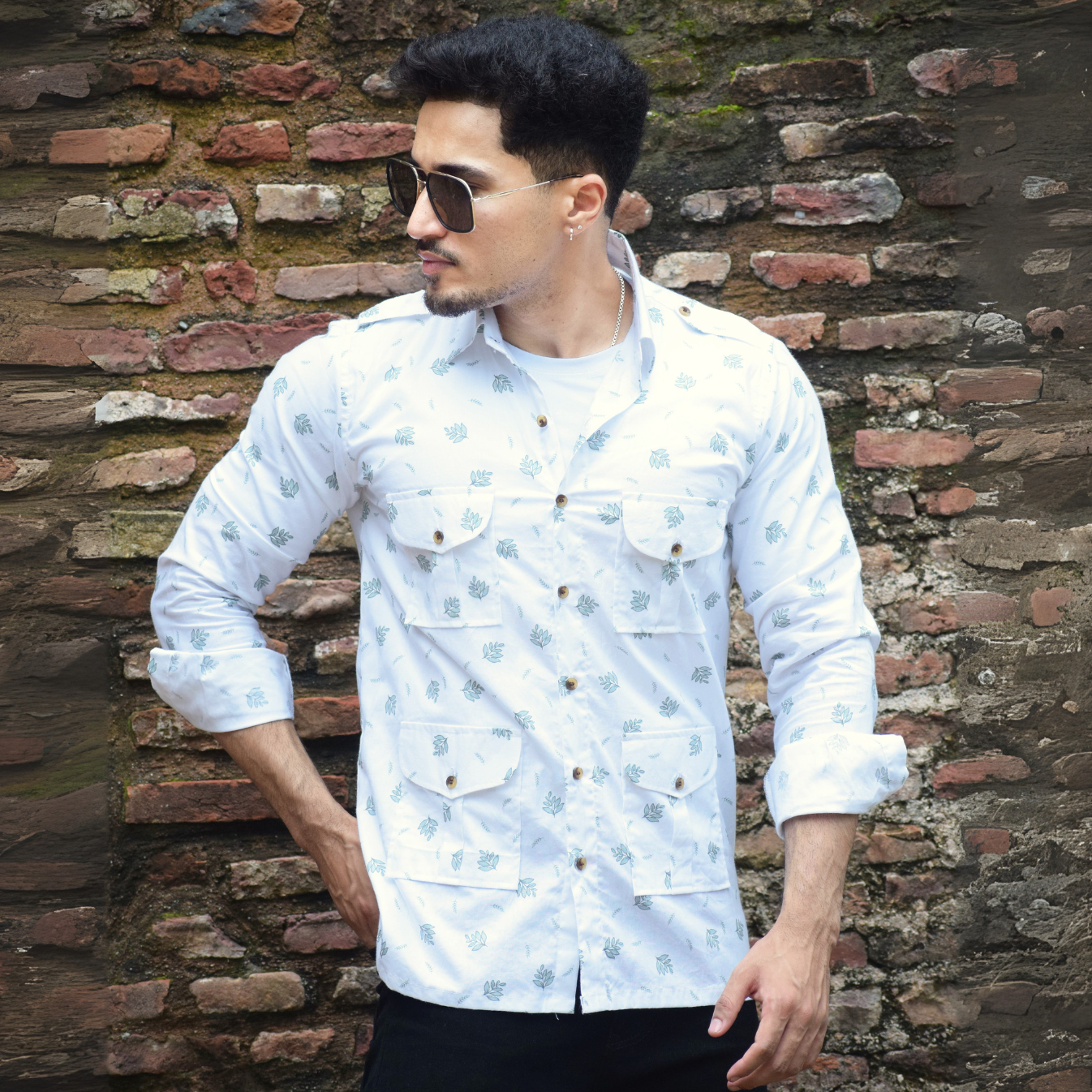 Man wearing a white patterned shirt against a brick wall