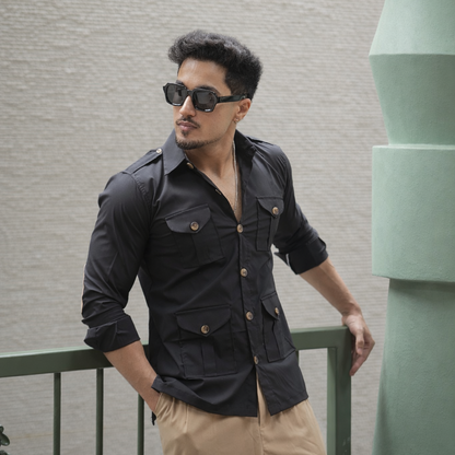 Man wearing a black hunting shirt standing against a wall