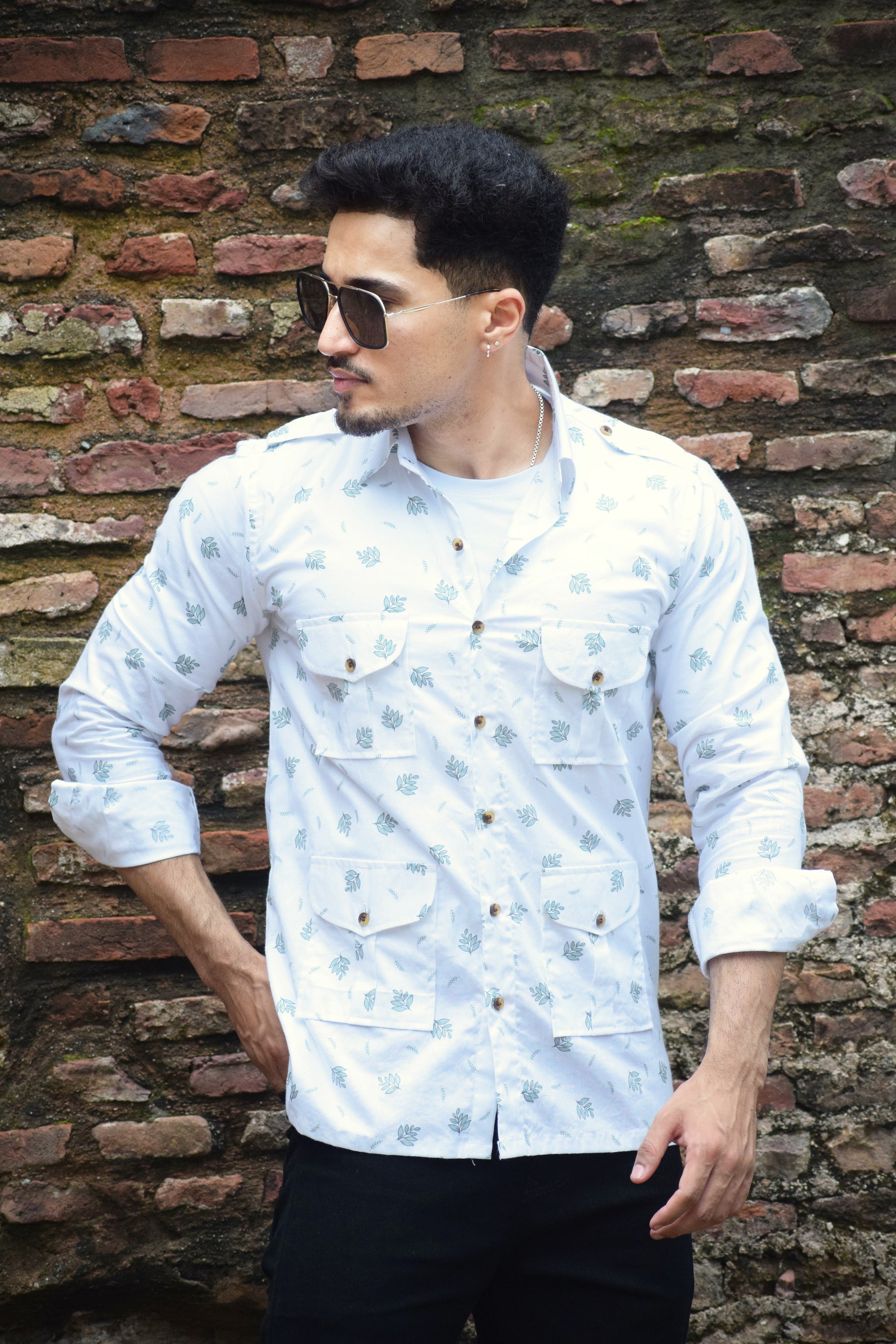 Man wearing a white patterned shirt against a brick wall