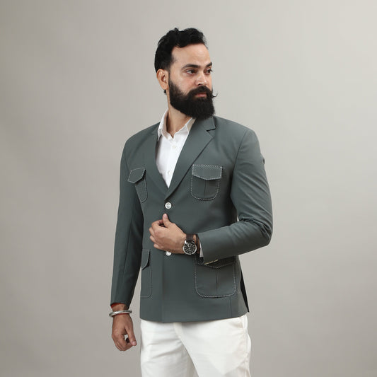 Man wearing a gray blazer, white shirt, and white pants against a plain background