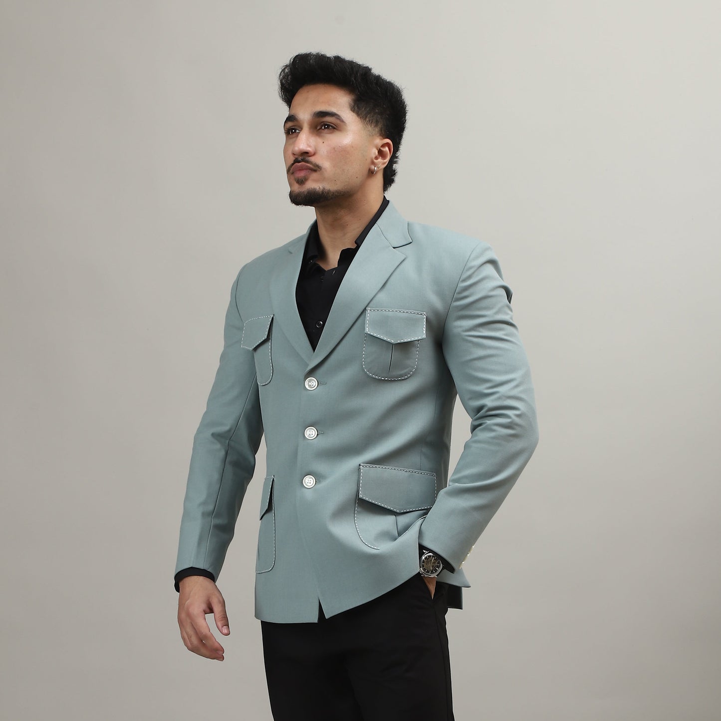 Person wearing a light blue blazer and black pants against a plain background