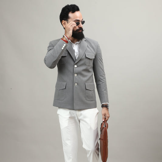 Person wearing a gray coat and white pants standing against a plain background