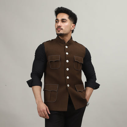 Person wearing a brown jacket with white buttons on a plain background