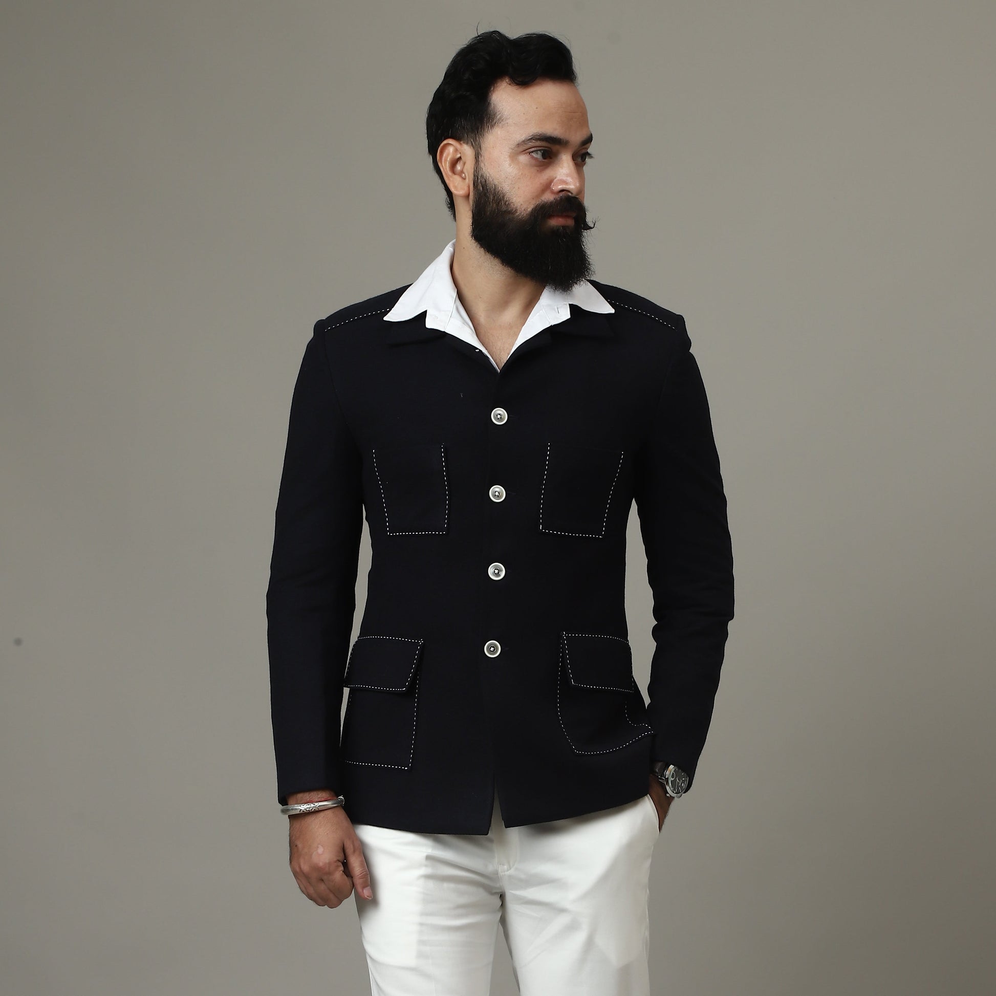 Man wearing a black jacket and white pants against a plain background