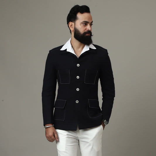 Man wearing a black jacket and white pants against a plain background