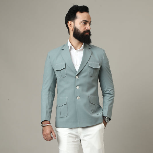 Person wearing a light blue blazer over a white shirt with white pants on a plain background