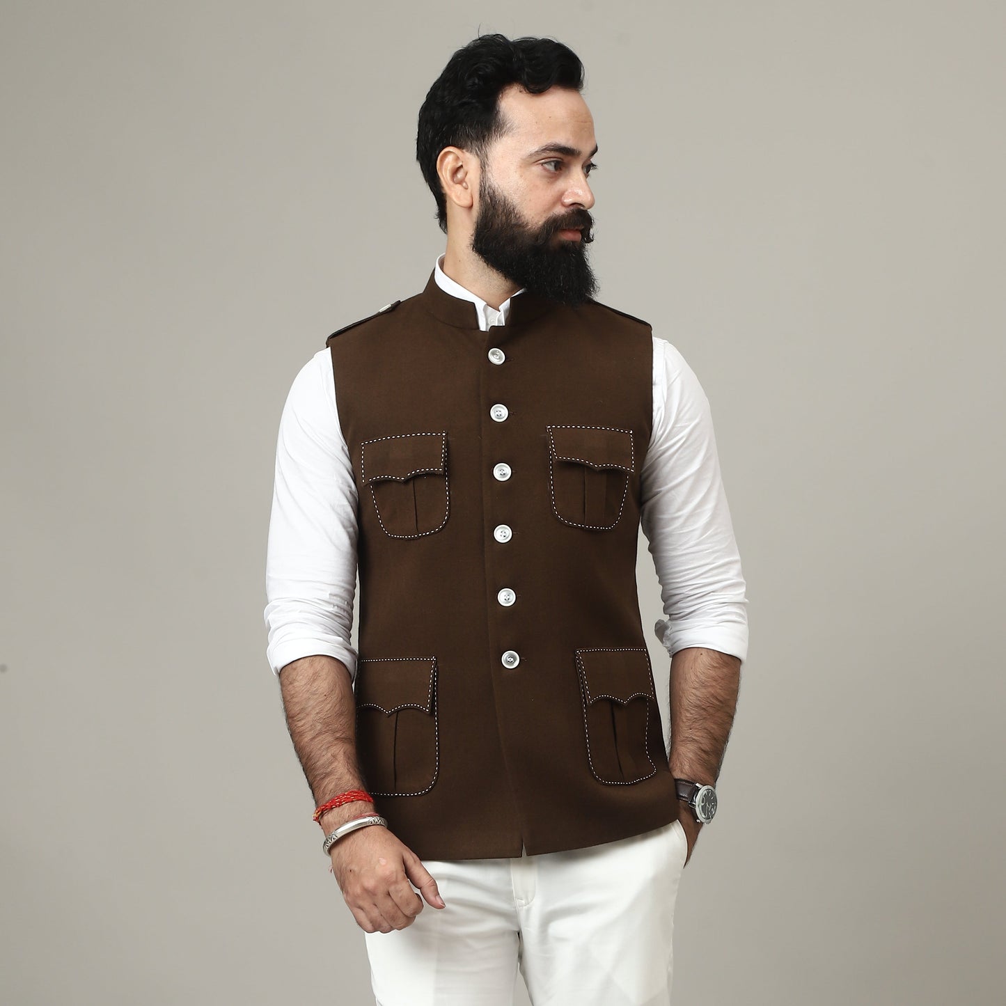 Person wearing a brown vest over a white shirt on a plain background