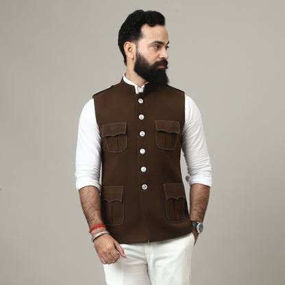 Person wearing a brown vest over a white shirt on a plain background