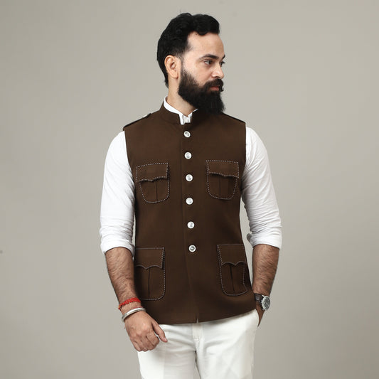Person wearing a brown vest over a white shirt on a plain background