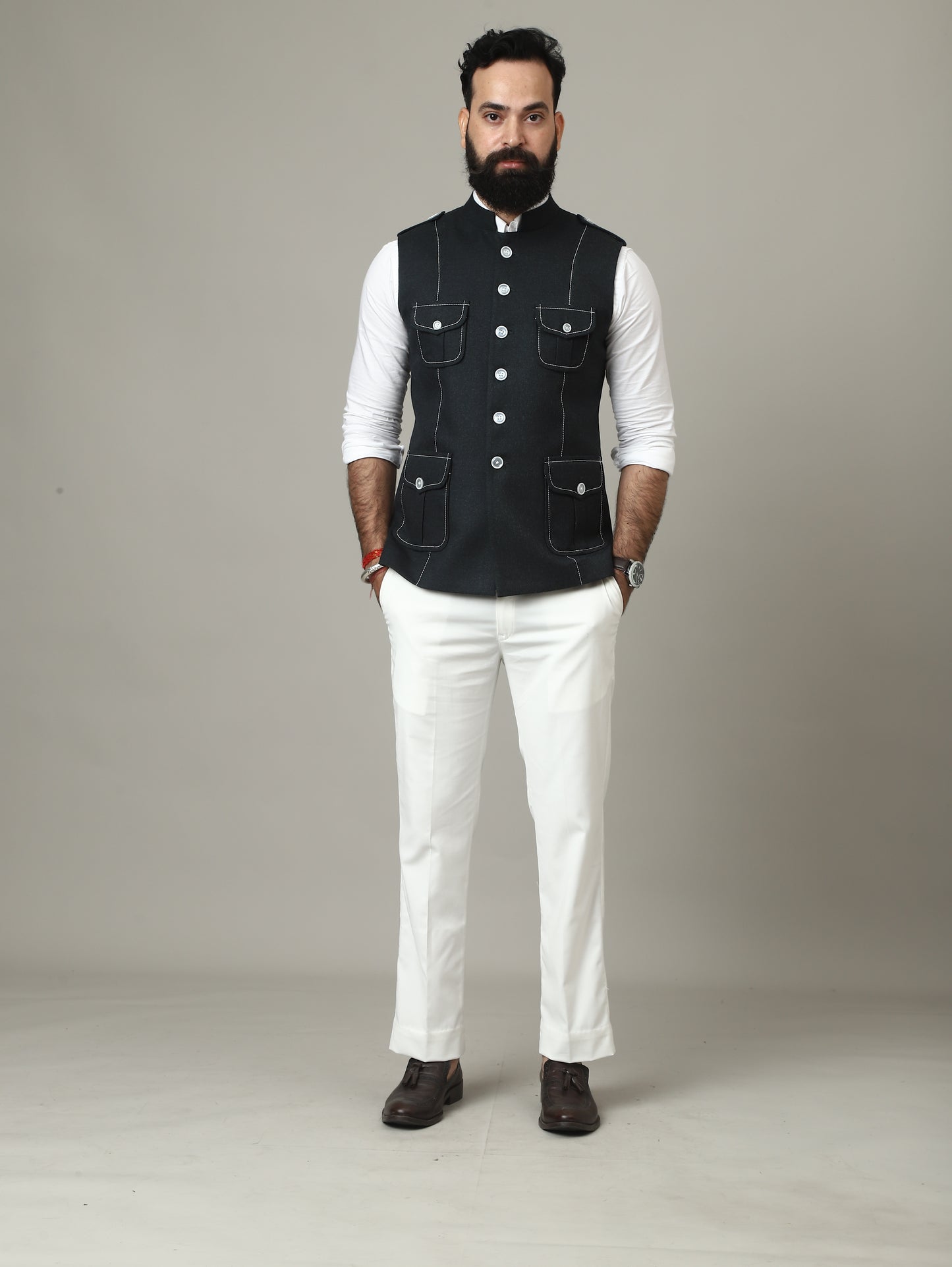 Man wearing a black vest over a white shirt on a plain background