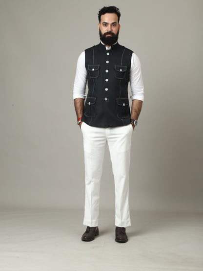 Man wearing a black vest over a white shirt on a plain background