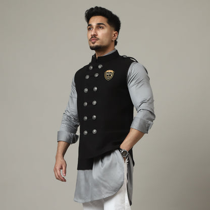 Man wearing a traditional outfit with a black vest on a plain background