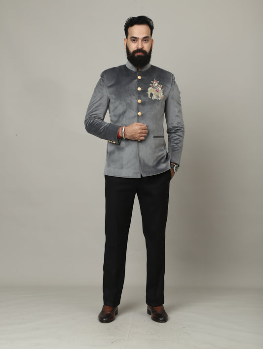 Person wearing a gray embroidered jacket and black pants on a plain background