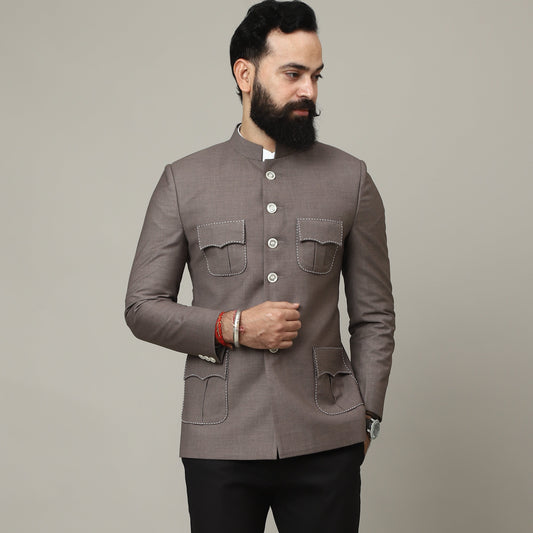 Man wearing a gray blazer and black pants against a plain background