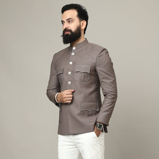 Man wearing a gray traditional jacket and white pants on a plain background