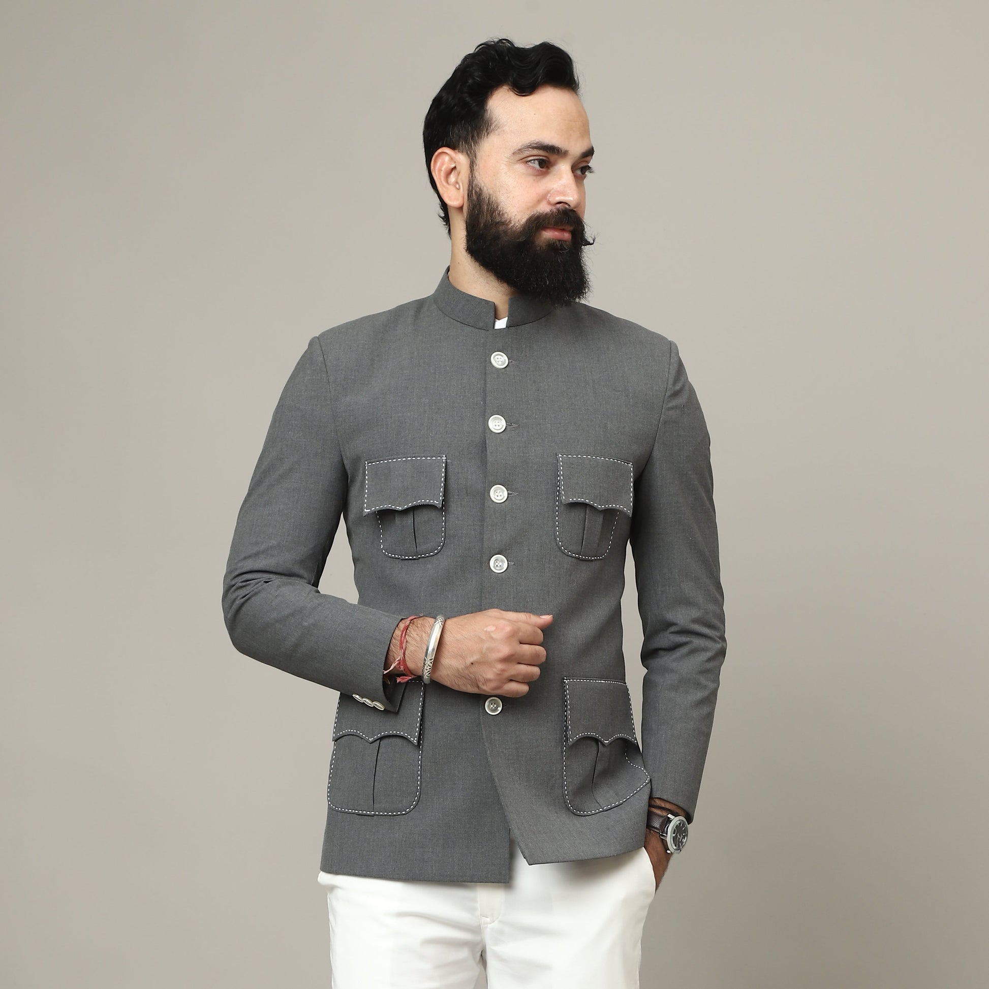 Man wearing a gray blazer and white pants against a plain background