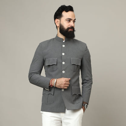 Man wearing a gray blazer and white pants against a plain background