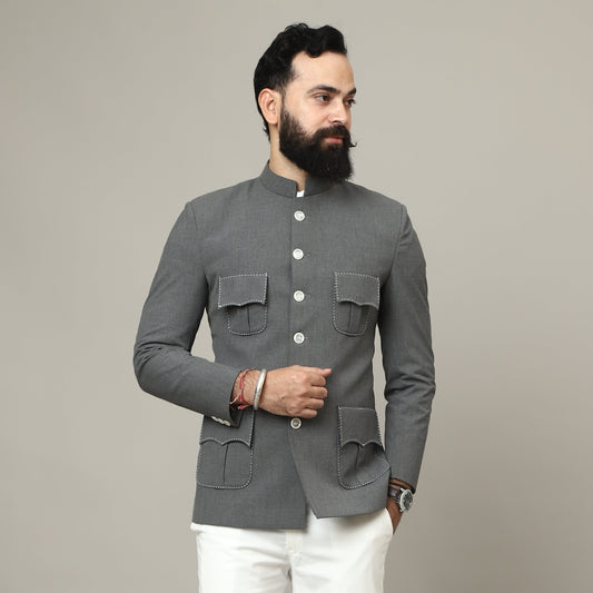 Man wearing a gray blazer and white pants against a plain background