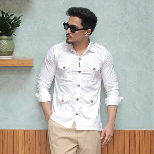 Man in a white shirt and beige pants standing on a wooden floor with a light green wall.