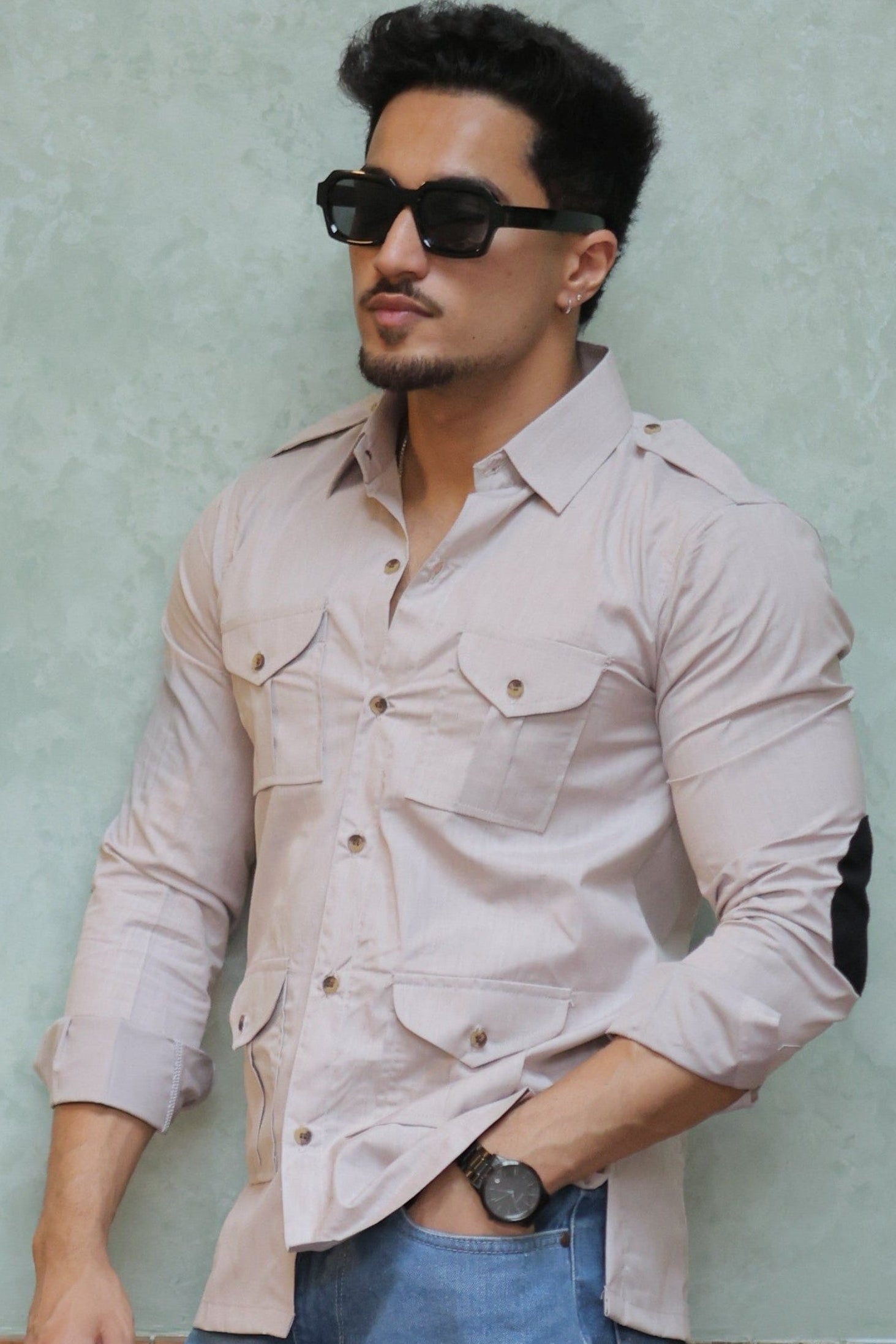 Man leaning against a wall with wooden panels and shelves holding plants.