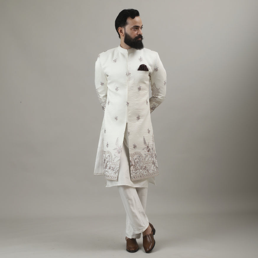 Person wearing a white embroidered outfit against a plain background