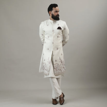 Person wearing a white embroidered outfit against a plain background